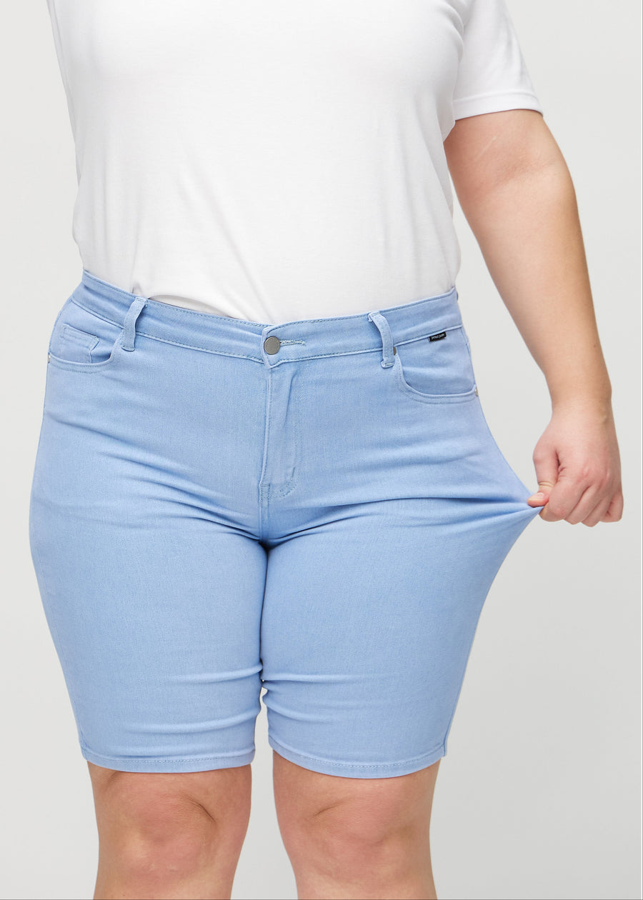 Plus-size model strækker shortsene ved låret for at vise stretch.