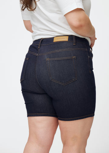 Dyb mørkeblå denim shorts til kvinder i farven Midnights set bagfra tæt på på plus-size model for at vise pasform og detaljer.