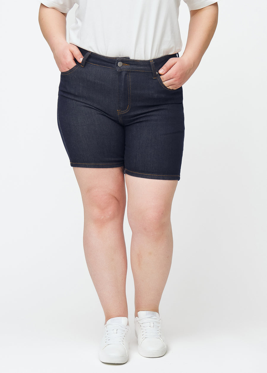 Dyb mørkeblå denim shorts til kvinder i farven Midnights med skinny pasform set forfra på plus-size model.