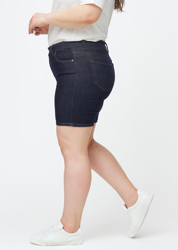 Dyb mørkeblå denim shorts til kvinder i farven Midnights med skinny pasform set fra siden på plus-size model.