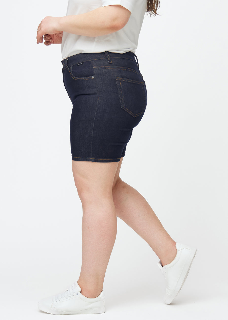 Dyb mørkeblå denim shorts til kvinder i farven Midnights med skinny pasform set fra siden på plus-size model.