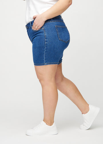 Mørk denim skinny short shorts set fra siden på en plus-size model.