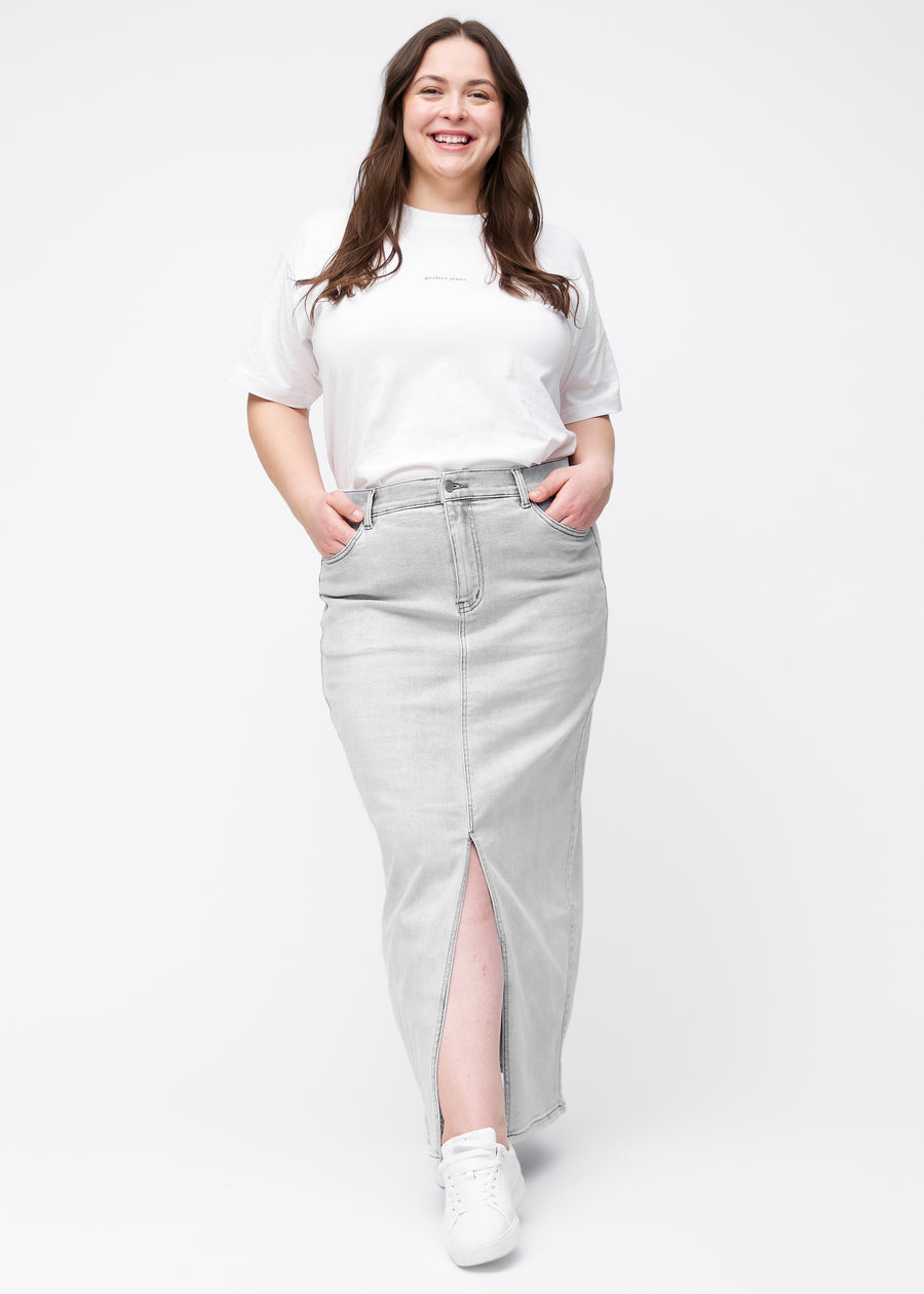 Fuldt billede af plus-size model i lang, lysegrå denimnederdel i farven Ashes med regulær pasform og slids foran.