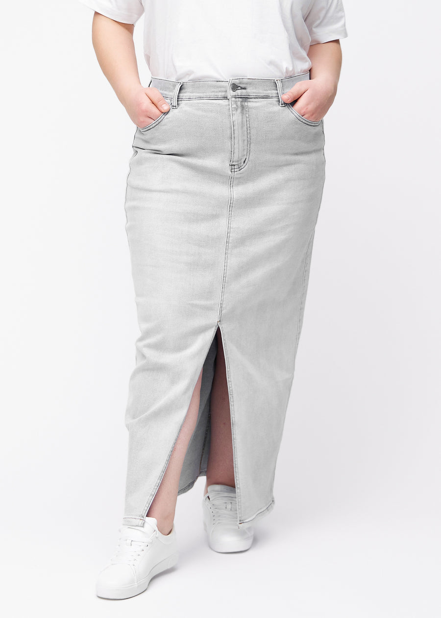Lang, lysegrå denimnederdel i farven Ashes med regulær pasform set forfra på plus-size model, med slids foran der starter lige under knæet.
