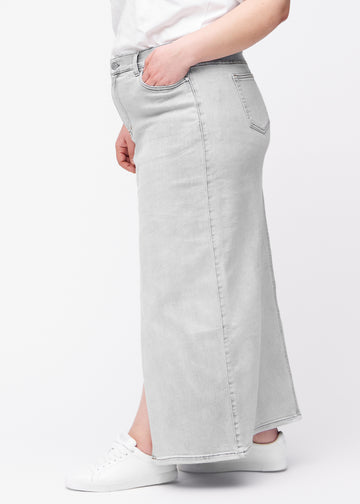 Lang, lysegrå denimnederdel i farven Ashes med regulær pasform set fra siden på plus-size model, med synligt slids foran.