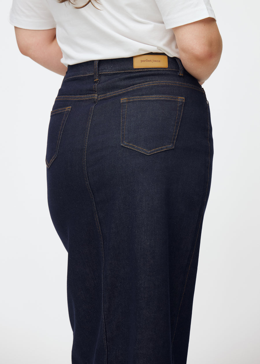 Lang dyb mørkeblå denim nederdel til kvinder i farven Midnights set bagfra tæt på på plus-size model for at vise pasform og detaljer.