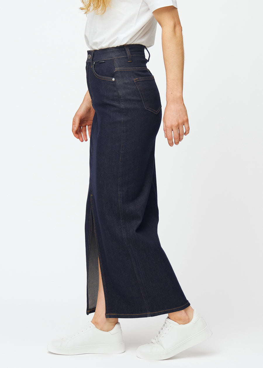 Lang dyb mørkeblå denim nederdel til kvinder i farven Midnights set fra siden på model, med synlig slids foran.