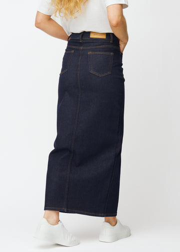 Lang dyb mørkeblå denim nederdel til kvinder i farven Midnights set bagfra, så hele nederdelens længde kan ses.