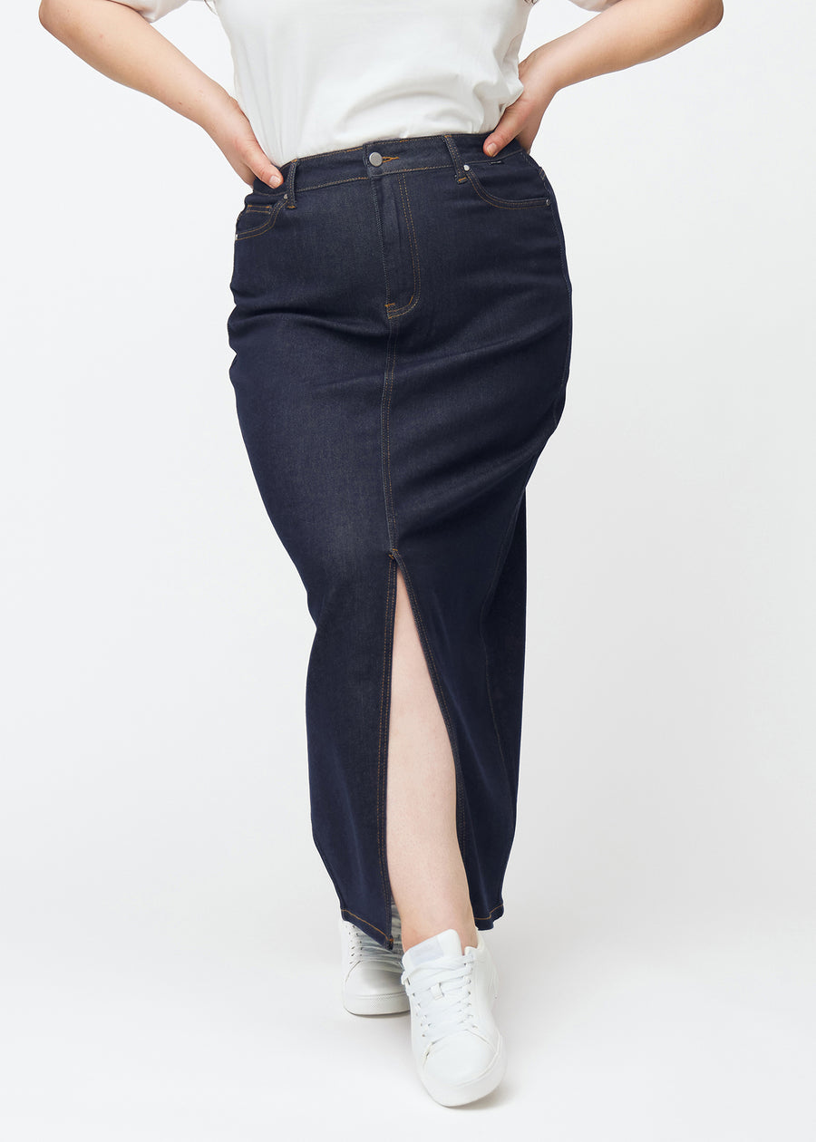 Lang dyb mørkeblå denim nederdel til kvinder i farven Midnights set forfra på plus-size model, med slids foran der starter lige under knæet.