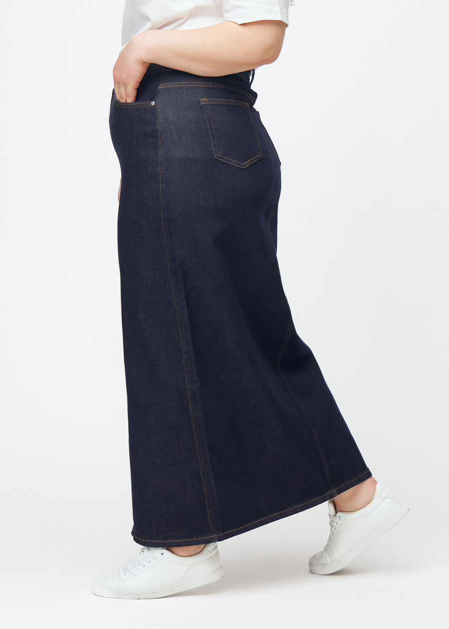 Lang dyb mørkeblå denim nederdel til kvinder i farven Midnights set fra siden på plus-size model, med synlig slids foran.
