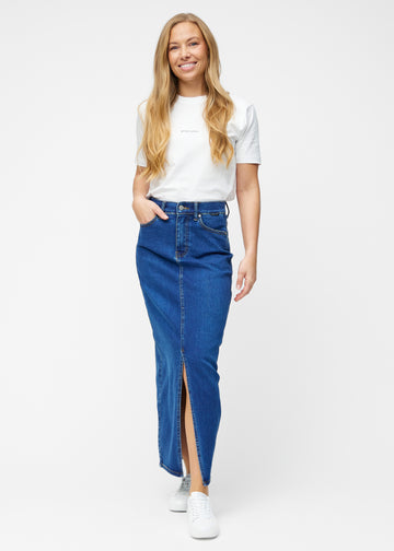 Fuldt billede af model i lang, mørkeblå denimnederdel i farven Oceans med regulær pasform og slids foran.