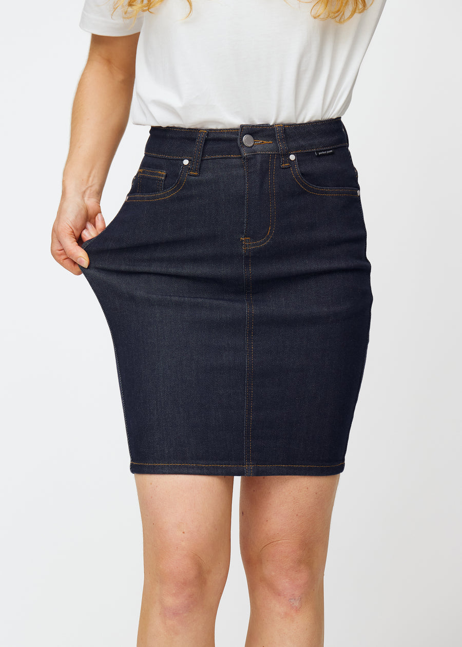 Model strækker dyb mørkeblå denim nederdel til kvinder i farven Midnights ved låret for at vise materialets stretch.