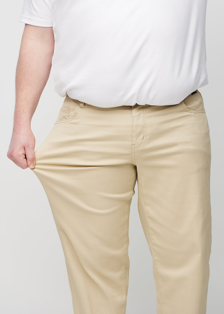 Plus-size model strækker jeansene ved låret for at vise stretch.