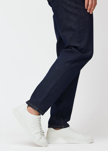 Dyb mørkeblå denim jeans til mænd i farven Midnights med regular pasform set tæt på ved anklerne for at vise den lige afslutning.