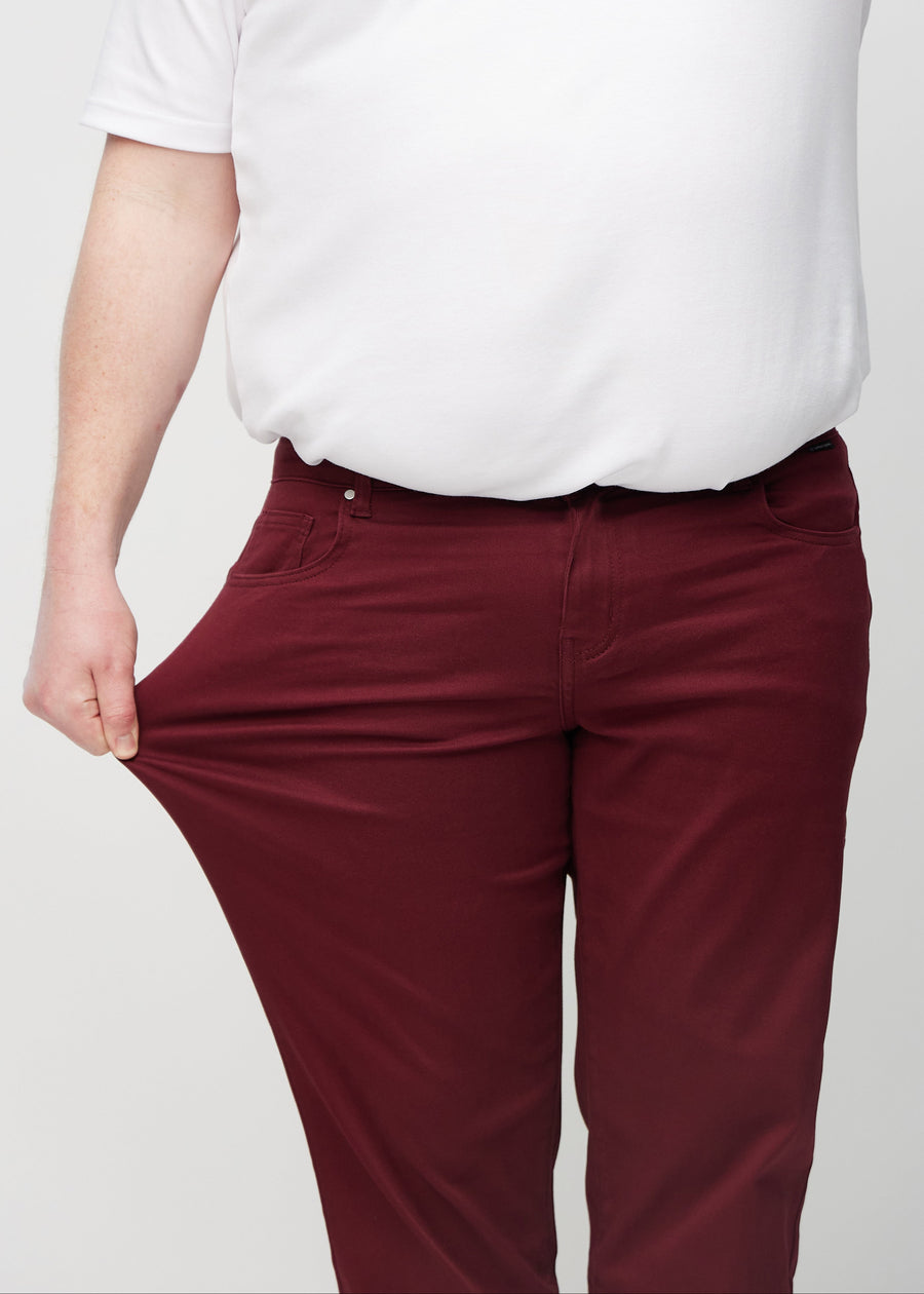 Plus-size model strækker jeansene ved låret for at vise stretch.
