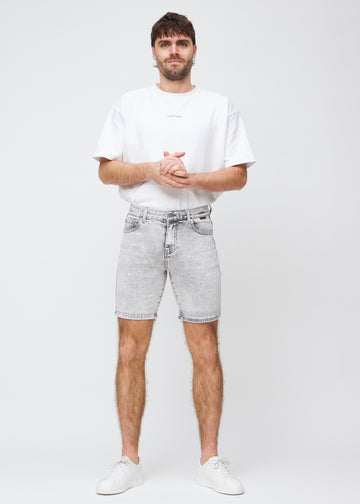 Fuldt billede af model i lysegrå denim middle-slim shorts.