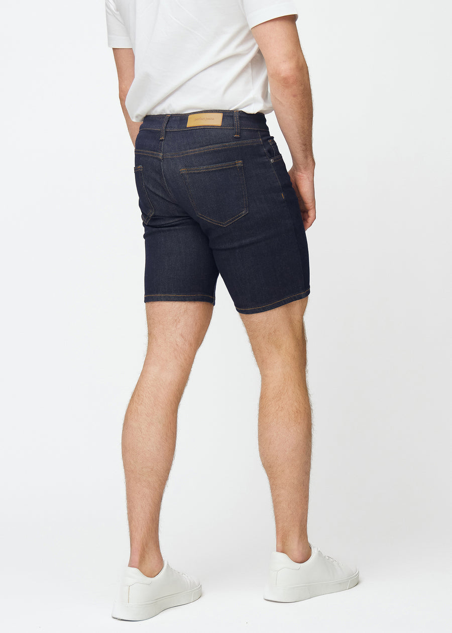 Dyb mørkeblå denim shorts til mænd i farven Midnights set bagfra, så længden til lige over knæet kan ses.