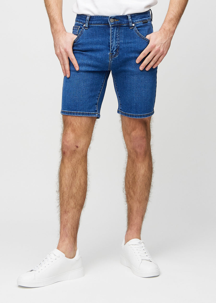 Mørk denim middle-slim shorts, som sidder lige langs låret og slutter lige over knæet, set forfra.