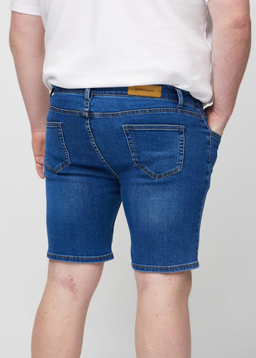 Mørk denim middle-slim shorts set bagfra tæt på en plus-size model for at vise detaljer.