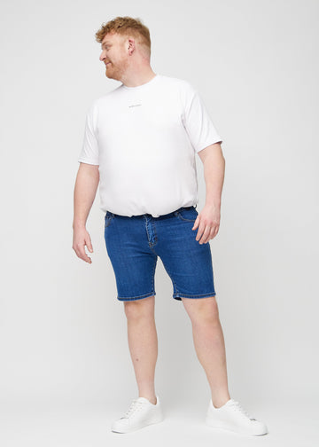 Fuldt billede af en plus-size model i mørk denim middle-slim shorts.