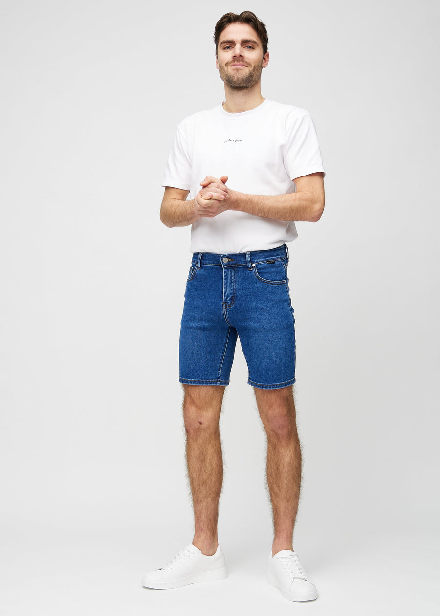 Fuldt billede af model i mørk denim middle-slim shorts.