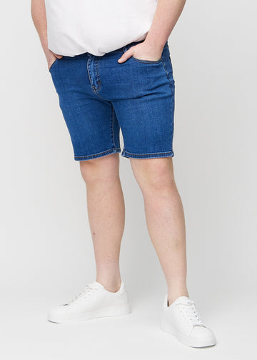 Mørk denim middle-slim shorts, som sidder lige langs låret og slutter lige over knæet på en plus-size model, set forfra.