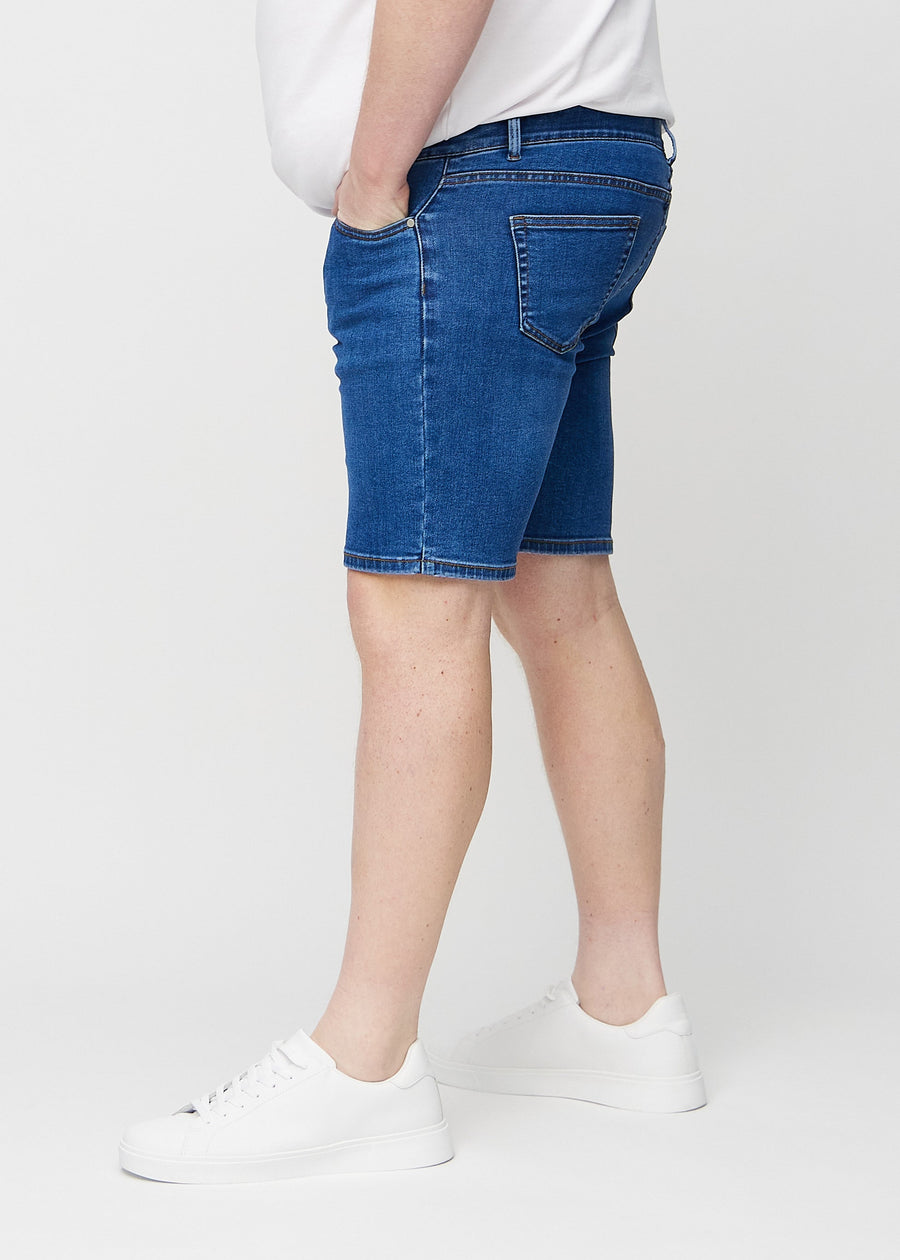 Mørk denim middle-slim shorts set fra siden på en plus-size model.