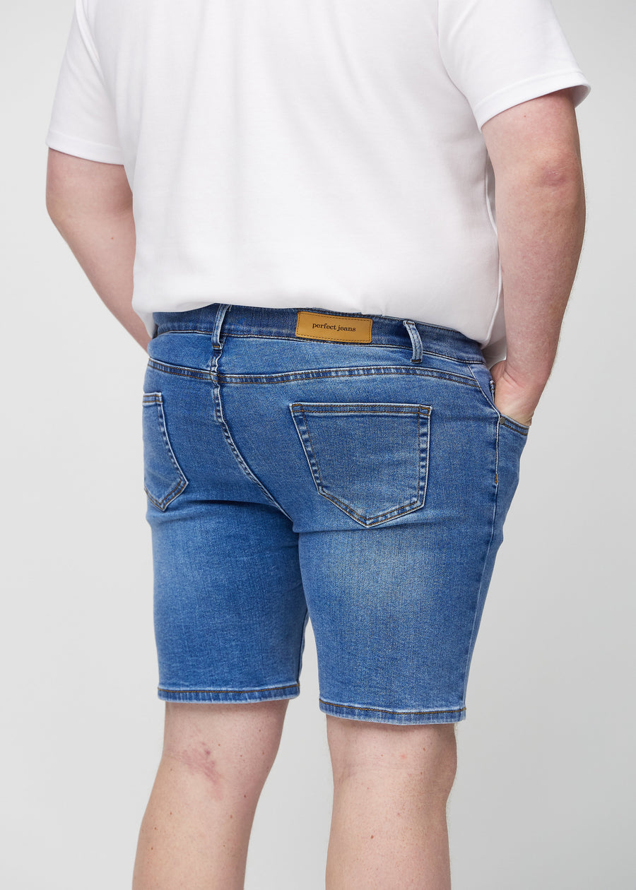 Denim middle-slim shorts set bagfra tæt på en plus-size model for at vise detaljer.