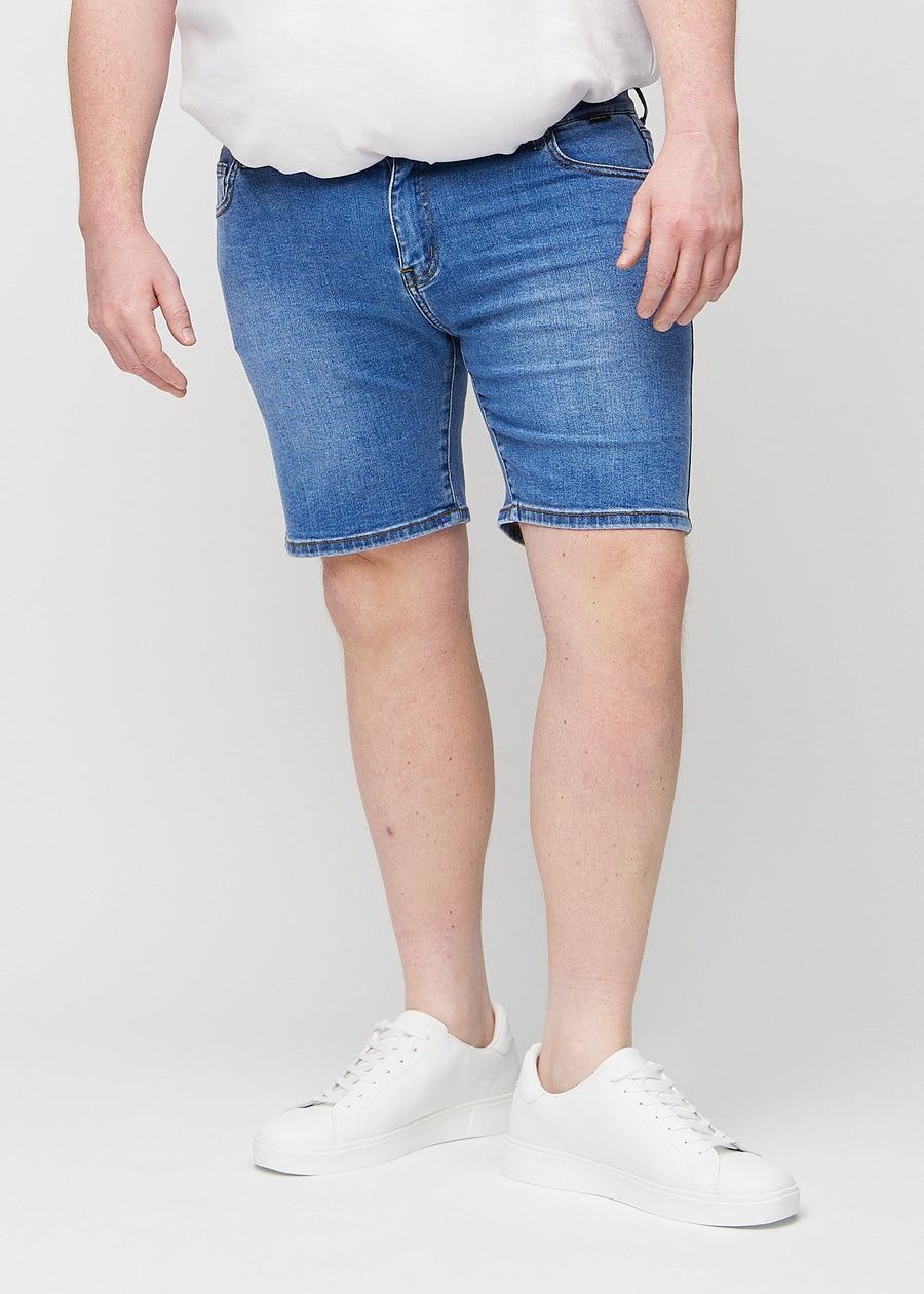 Denim middle-slim shorts, som sidder lige langs låret og slutter lige over knæet på en plus-size model, set forfra.