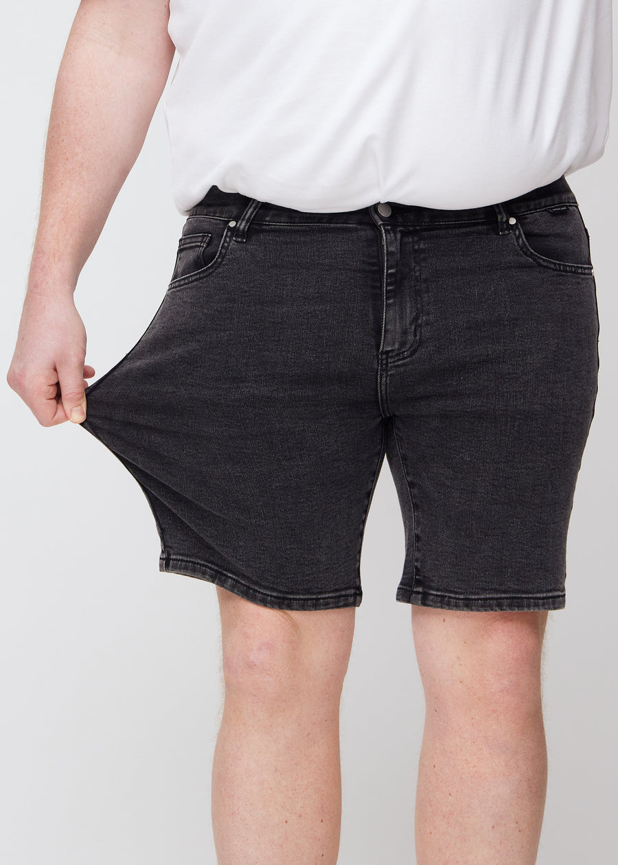 Plus-size model strækker shortsene ved låret for at vise stretch.