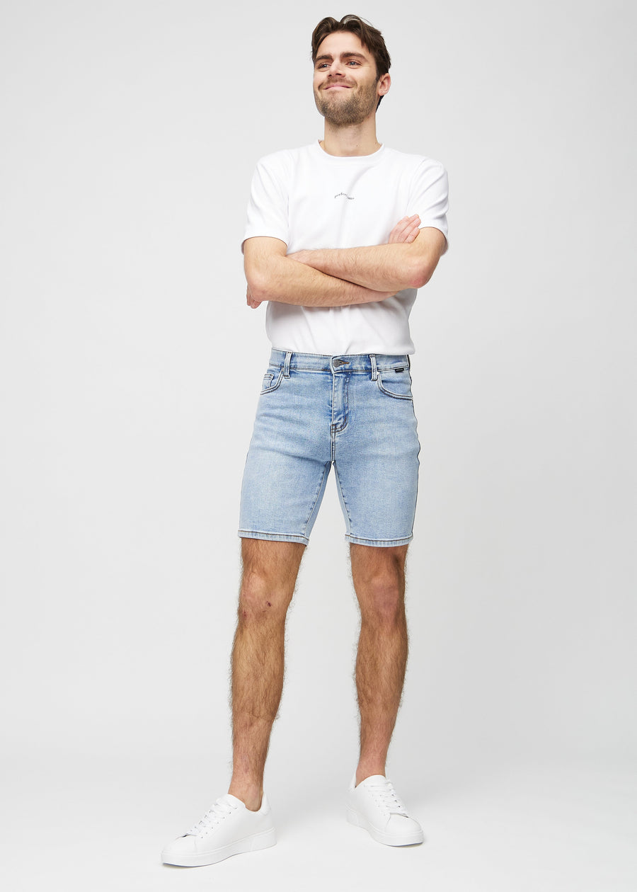 Fuldt billede af model i lys denim middle-slim shorts.