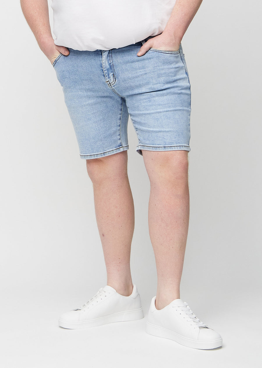 Lys denim middle-slim shorts, som sidder lige langs låret og slutter lige over knæet på en plus-size model, set forfra.