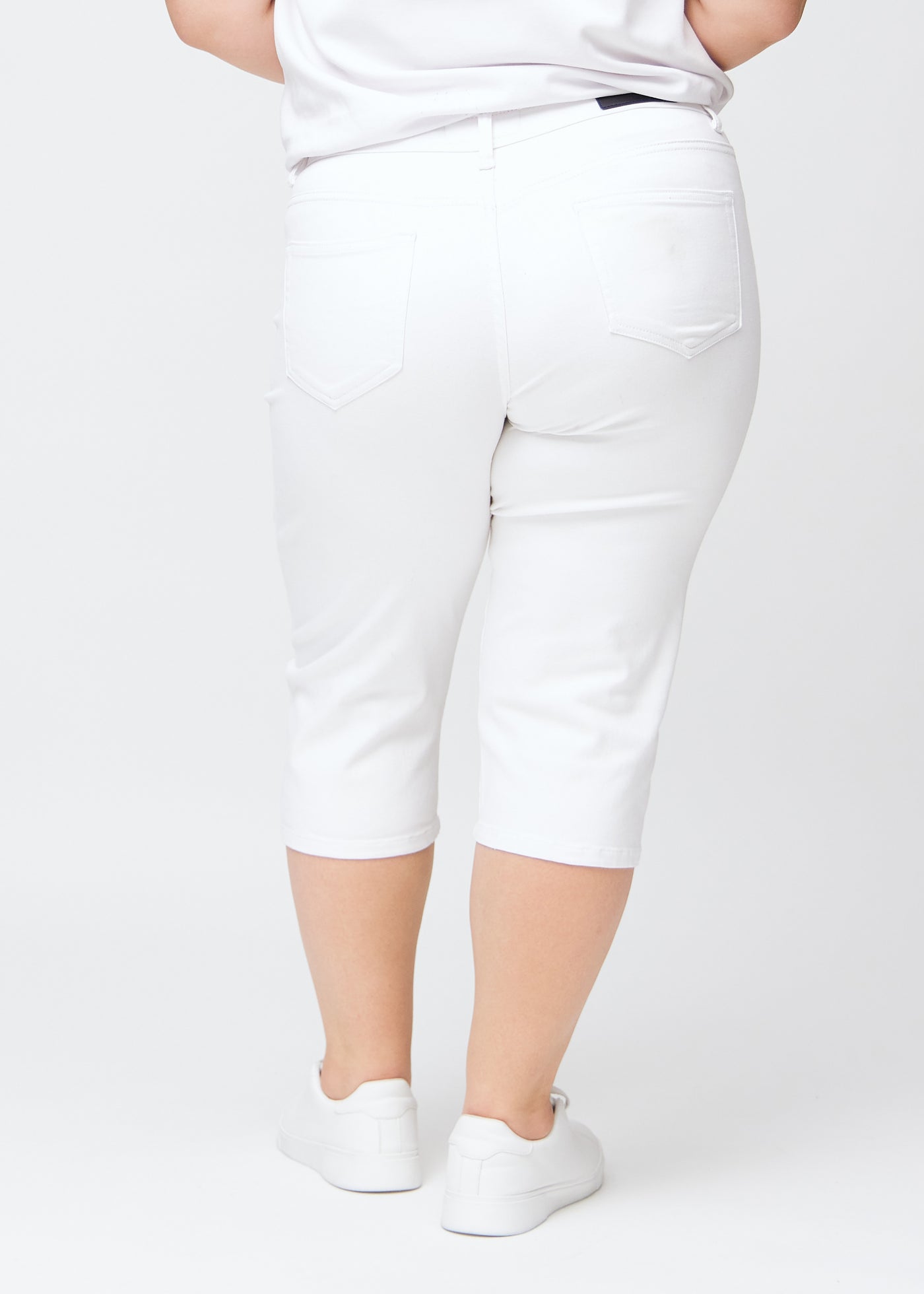 Hvide slim capris set bagfra på en plus-size model – tydeligt billede af hele produktet og lommer.