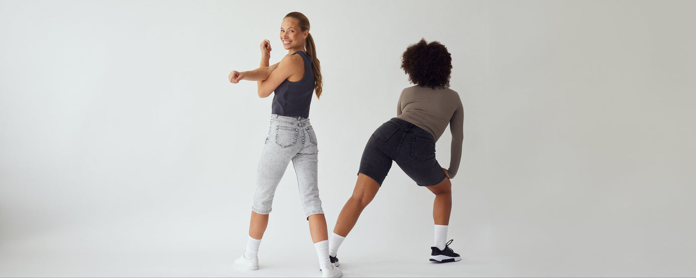 To kvinder i grå denim shorts og capris, der strækker ud, for a t vise hvor strækbare de er.