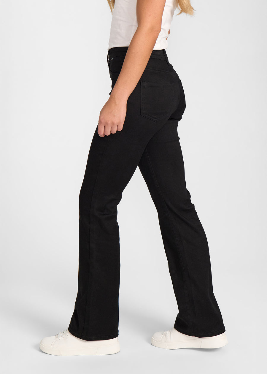 Sort bootcut jeans, modelnavn Ravens, som sidder tæt om hofter og lår med et let svaj fra knæet og ned, set fra siden på model.