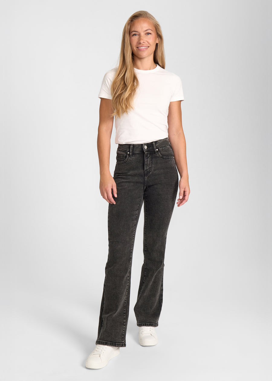 Fuldt billede af model i mørkegrå denim bootcut jeans.