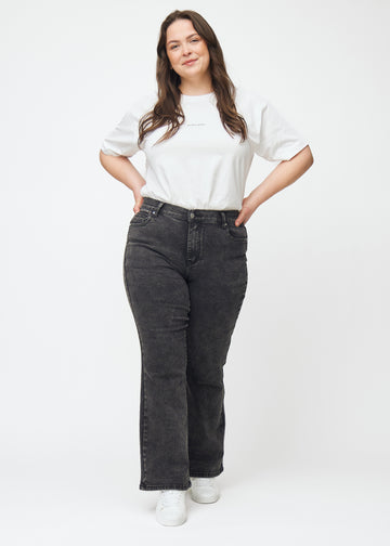 Plus-size model går ind i billedet, strækker i jeansene, viser dem frem ved at dreje rundt og forlader derefter billedet.